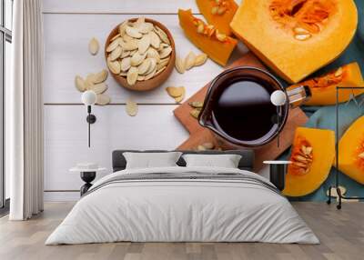 Flat lay composition with pumpkin seed oil in glass pitcher on white wooden table. Space for text Wall mural