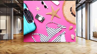 Flat lay composition with suitcase and beach objects on pink background Wall mural