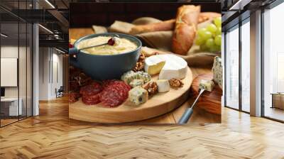 Fondue pot with tasty melted cheese, forks and different snacks on wooden table Wall mural