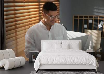 Freelancer working on laptop near window indoors Wall mural