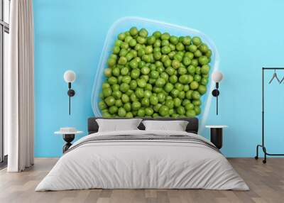 Fresh peas in glass container on light blue background, top view Wall mural