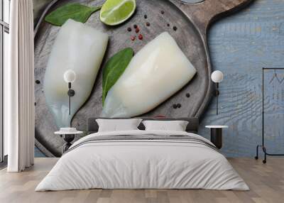 Fresh raw squid tubes with lime, herbs and tomato on grey wooden table, top view Wall mural