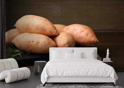 Fresh raw sweet potatoes and rosemary on wooden table, closeup Wall mural