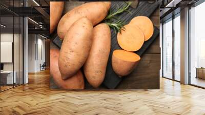 Fresh raw sweet potatoes and rosemary on wooden table, top view Wall mural