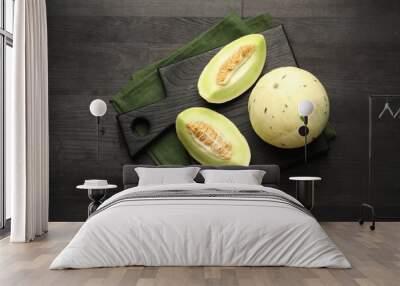 Fresh whole and cut honeydew melons on black wooden table, top view Wall mural