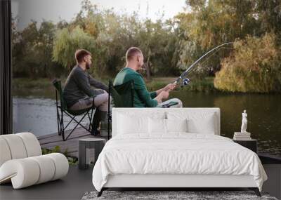 Friends fishing on wooden pier at riverside. Recreational activity Wall mural