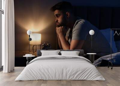 Frustrated man suffering from insomnia on bed Wall mural