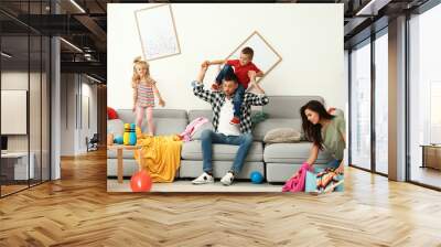 Frustrated mother trying to clean up mess while father playing with children in room Wall mural