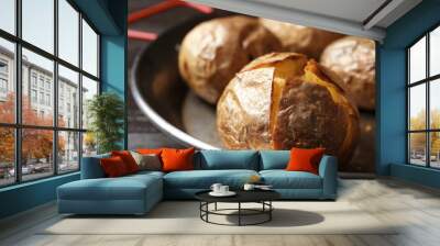 Frying pan with tasty baked jacket potatoes on wooden table, closeup Wall mural