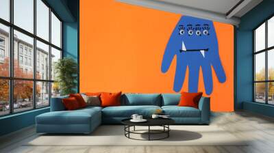 Funny blue hand shaped monster on orange background, top view with space for text. Halloween decoration Wall mural