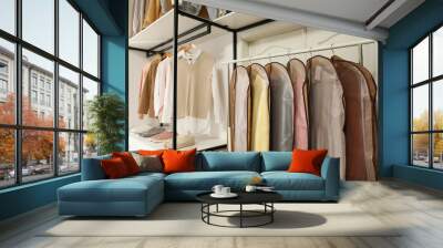 Garment bags with clothes on rack in dressing room Wall mural