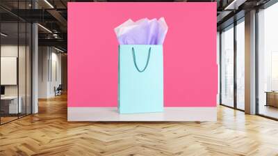 Gift bag with paper on white table against pink background Wall mural