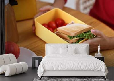 Girl with lunch box of healthy food at wooden table in kitchen, closeup Wall mural