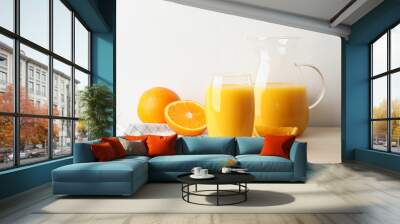 Glass and jug of orange juice and fresh fruits on wooden table Wall mural