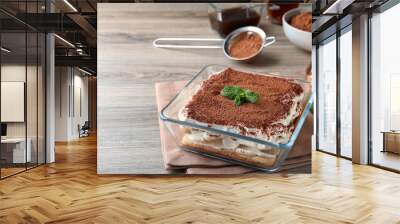 Glass bowl with delicious tiramisu cake on wooden table, space for text Wall mural