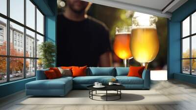 Glasses of cold tasty beer on wooden table outdoors Wall mural