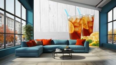 Glasses of refreshing iced tea on light table against white wooden background. Space for text Wall mural