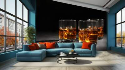 Golden whiskey in glasses with ice cubes on table. Space for text Wall mural