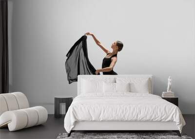 Graceful young ballerina practicing dance moves with black veil on white background Wall mural