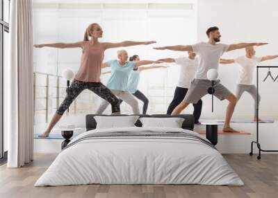 Group of people in sportswear practicing yoga indoors Wall mural