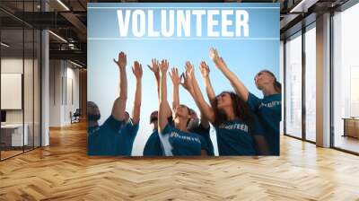 Group of volunteers raising hands outdoors, low angle view Wall mural