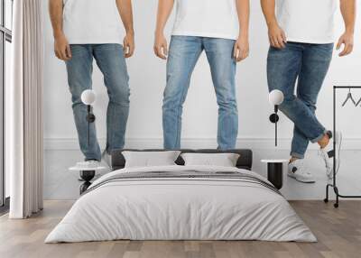 Group of young men in stylish jeans near white wall, closeup Wall mural