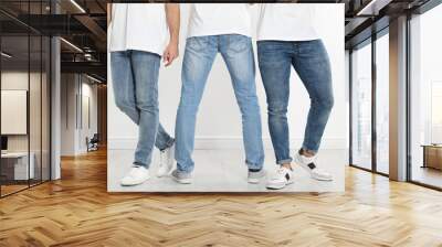 Group of young men in stylish jeans near white wall, closeup Wall mural