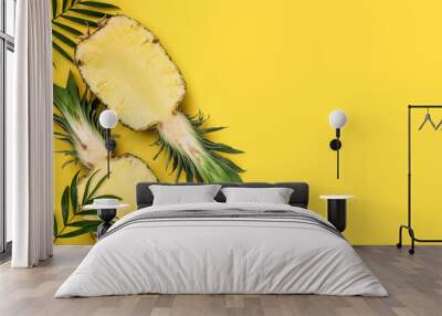 Halves of ripe pineapple and green leaves on yellow background, flat lay. Space for text Wall mural