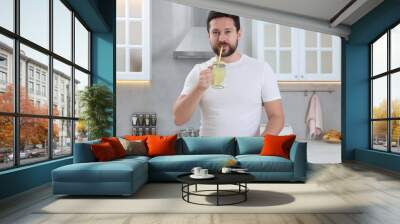 Handsome man drinking water with lemon in kitchen Wall mural