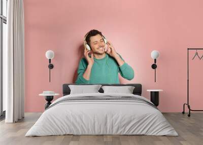 Handsome man listening to music with headphones on color background Wall mural