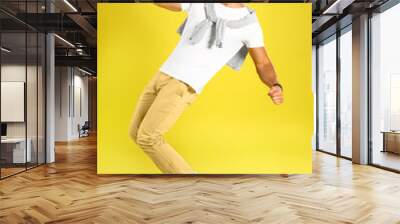 Handsome young man dancing on yellow background Wall mural