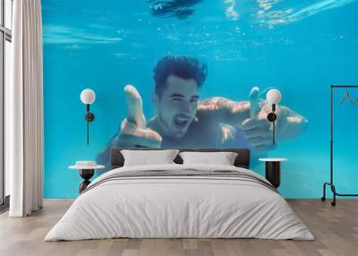 Handsome young man swimming in pool, underwater view Wall mural