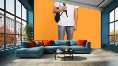 Handsome young man with backpack on orange background Wall mural