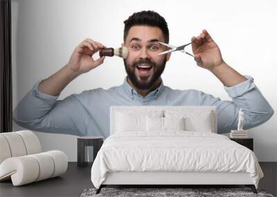 Handsome young man with mustache holding scissors and shaving brush on white background Wall mural