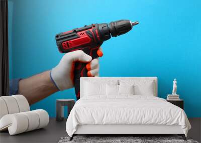 Handyman holding electric screwdriver on light blue background, closeup Wall mural