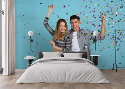 Happy couple and falling confetti on light blue background Wall mural