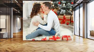 Happy couple kissing near Christmas tree at home Wall mural