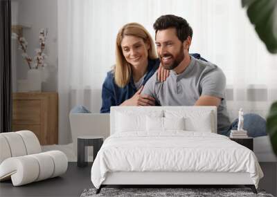 Happy couple with laptop on bed at home Wall mural