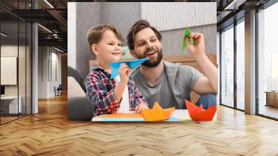 Happy dad and son playing with paper planes at home Wall mural