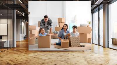 Happy family having fun while unpacking moving boxes at their new home Wall mural