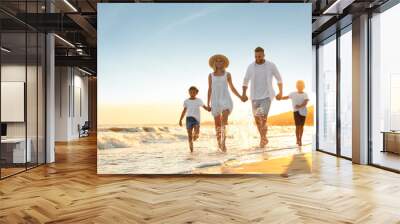 Happy family on sandy beach near sea at sunset Wall mural