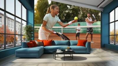 Happy family playing tennis on court outdoors Wall mural