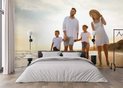 happy family walking on sandy beach near sea at sunset Wall mural