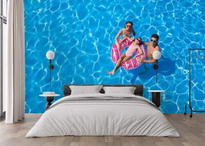 Happy family with inflatable ring in swimming pool, space for text. Summer vacation Wall mural