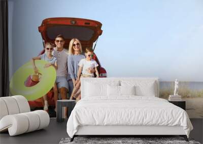 Happy family with inflatable ring near car at beach on sunny day Wall mural