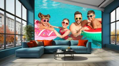 Happy family with inflatable rings in swimming pool Wall mural