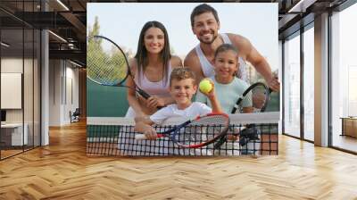 Happy family with tennis rackets on court outdoors Wall mural