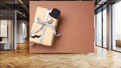 Happy Father's Day. Gift box with paper hat and moustache on brown background, top view Wall mural