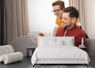 Happy father and his teenager son with tablet computer at home Wall mural