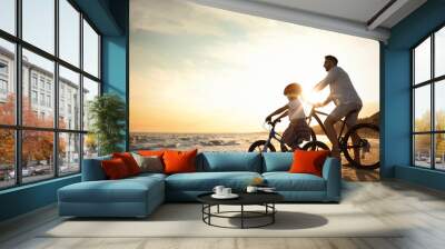 Happy father with son riding bicycles on sandy beach near sea at sunset Wall mural